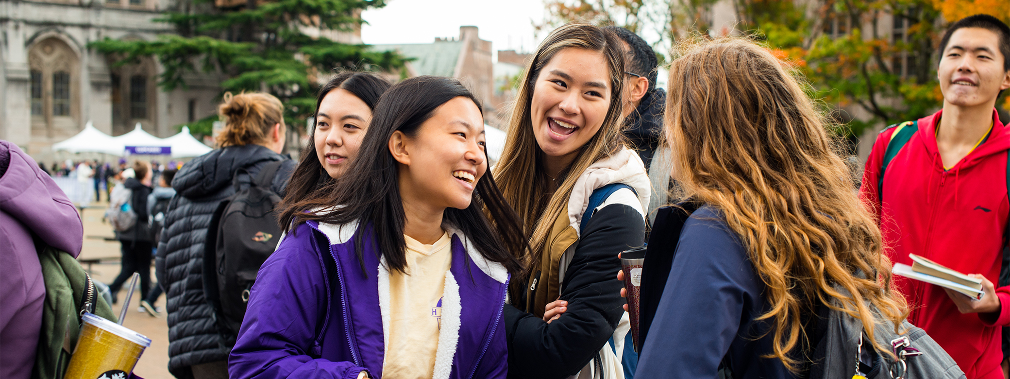 Group of smiling people talk to each other outside.