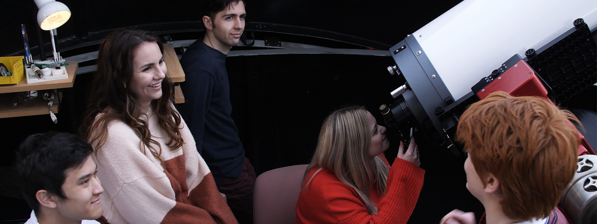 group of students around telescope