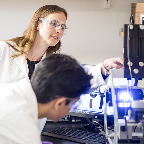 Ashleigh Therberge and research team members looking at equipment in her UW chemistry lab.