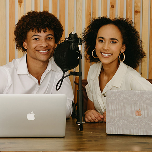 Tiana Cole + Brad Blackburn III seated behind a microphone.